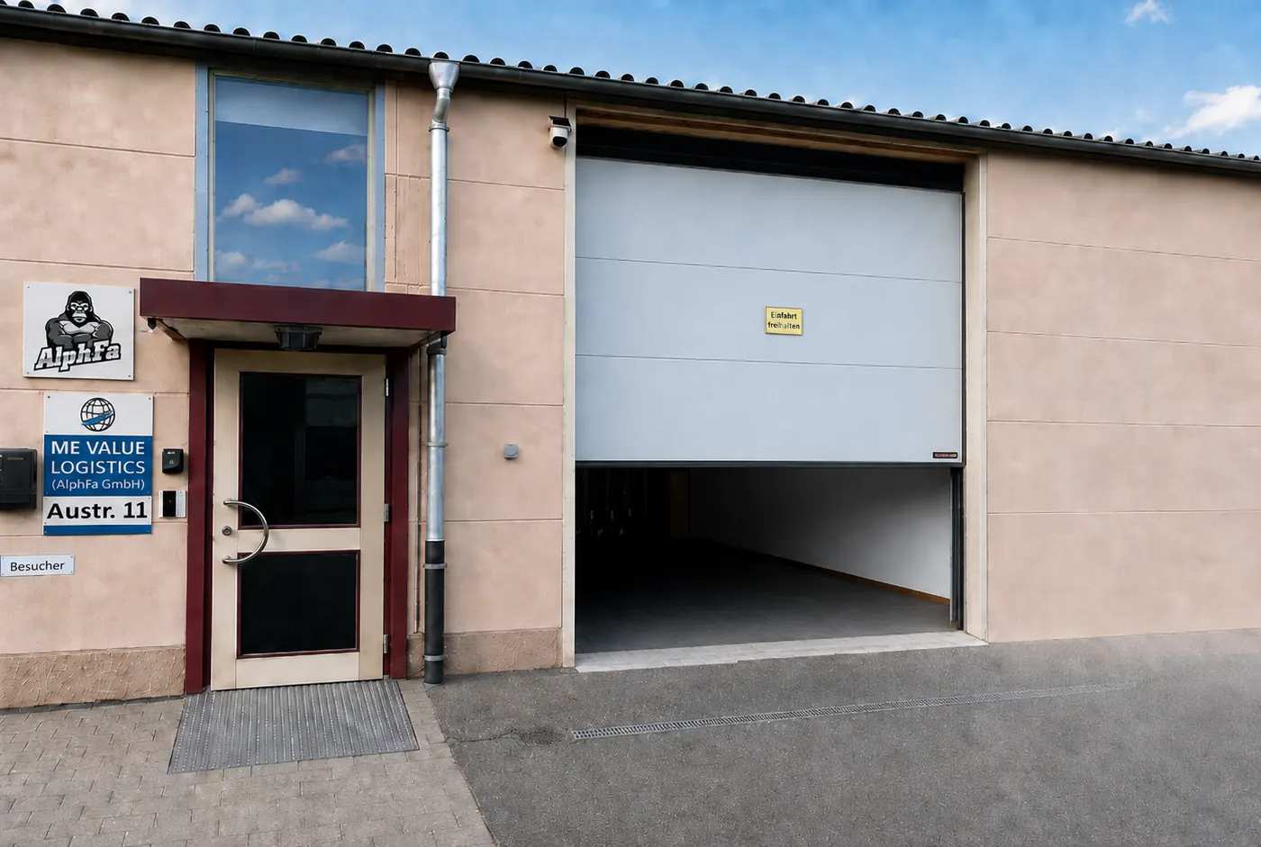 Betriebsgebäude der AlphFa GmbH mit Eingang, Firmenschild und geöffnetem Rolltor zur Warenannahme